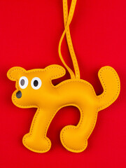 close up of leather yellow dog keychain with big funny eyes on  red  background