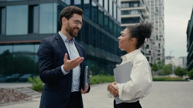 Two multiracial business colleagues meeting in city high five hello hi greeting African American woman girl female businesswoman talking happy discuss startup with Caucasian man guy male businessman