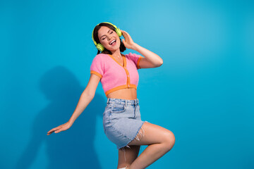 Attractive young woman in casual summer outfit enjoying music with headphones, posing dynamically...