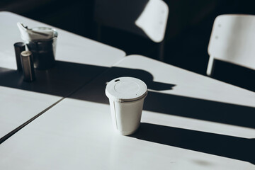 Recycled white disposable cup with paper lid in cafe in the morning.