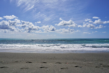 Footprints on sandy beach by ocean under clear sky