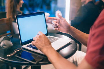 Crop ethnic man using netbook in restaurant