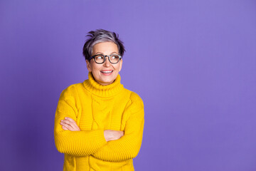Photo portrait of pretty senior female look empty space crossed hands wear trendy yellow outfit isolated on violet color background
