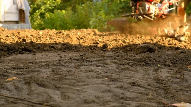 A man plows the land with a walk-behind tractor. Selective focus. Nature.
