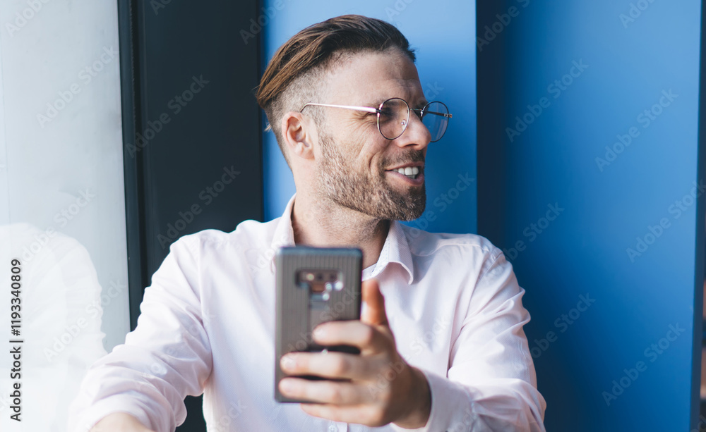 Aufkleber male blogger in optical eyewear for eyes correction looking away and smiling while creating web publ