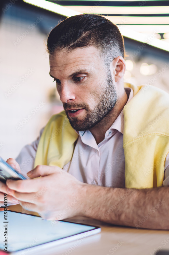Poster smart casual male blogger enjoying time for mobile networking using touch pad for planning content p
