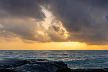 Obraz premium sunrise dramatic sky over sea horizon from rocky shore at dawn long exposure shot