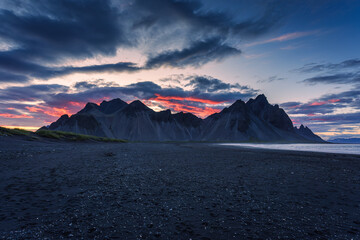 Sunset over volcanic Vestrahorn mountain on black sand beach in summer at Iceland