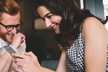 Woman using smartphone and laughing with friend