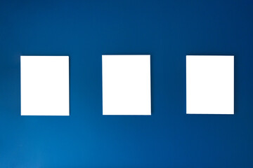 Three empty square canvas frames arranged on deep blue wall