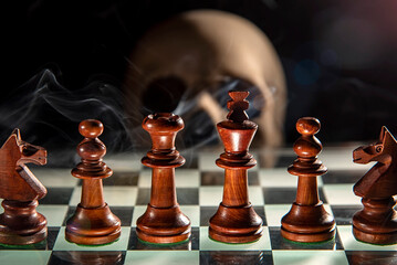 Piezas de ajedrez sobre un tablero con una calavera de fondo y humo, que simbolizan la mortalidad y la estrategia. © Jossfoto