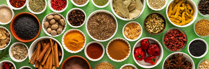 Fresh, multicolored spices and herbs set against a gentle green background, creating a vivid, fragrant display perfect for food inspiration, banner