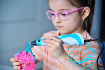 Child plays with a 3D pen. The girl creates a 3D toy.