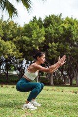 Brunette Woman Doing Squats on Grass in Park, Filming Herself with Mobile Phone