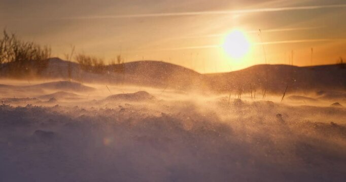 Frozen landscape of snow covered field after a blizzard, ice desert, winter wonderland, wind blows snowflakes, morning sunlight, polar sunrise 4K cinematic video
