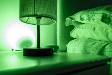 Smart LED lighting seen in a soft green hue seen on a bedside table. The wireless smart light can...