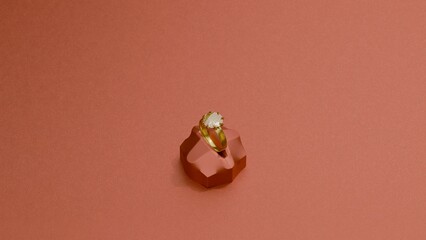 Elegant solitaire ring on faceted platform with red backdrop
