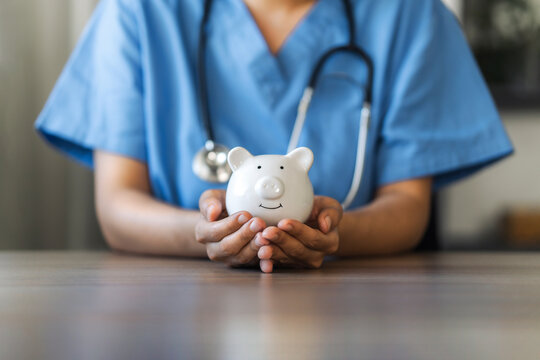 Nurse or doctor with stethoscope holding piggy bank in hand. Concept of medical expenses, finance, saving money, health insurance, medicine, donation and pension. Healthcare service cost.