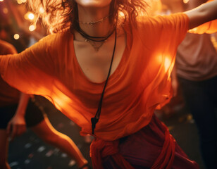 An Asian woman dressed in a bright orange red dress moves with energy, the bold color and industrial background creating a striking, modern contrast.