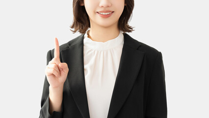 人差し指を立てて案内する若い女性・ビジネスウーマン