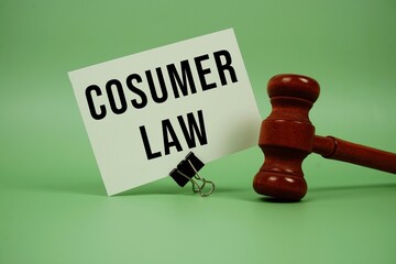 Consumer Law text message on paper card with wooden gavel on green background