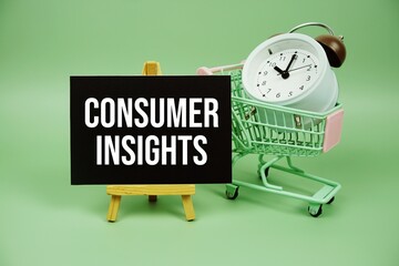 Consumer Insights text message on paper card with alarm clcok and trolley shopping cart on green background