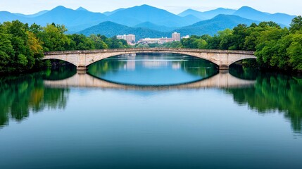 Serene bridge reflecting on calm water with mountains.