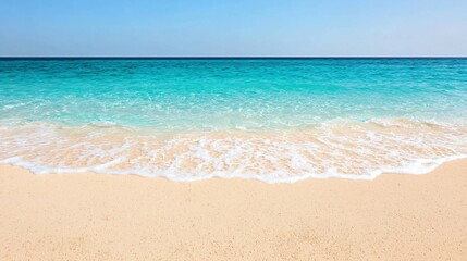 Fototapeta premium Soft waves lapping on a pristine sandy beach, turquoise ocean under a clear blue sky.