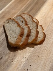 Small slices of sourdough bread, lined up on a wood cutting board.