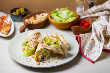 Chicken bacon caeser wrap. Chicken breast fillet wraps on green plate on light wooden background