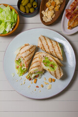 Chicken bacon caeser wrap. Chicken breast fillet wraps on green plate on light wooden background. View from above, top view