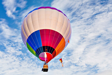 Fototapeta premium Colorful hot air balloon flying over blue sky with white clouds