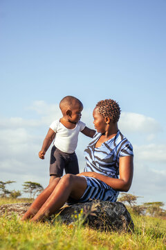 A beautiful young African woman playing outdoors with her baby boy at sunset