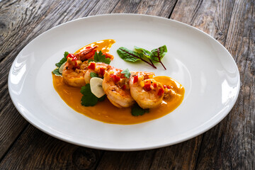 Appetizer of fried shrimps in mango sauce with garlic and chili pepper on wooden table