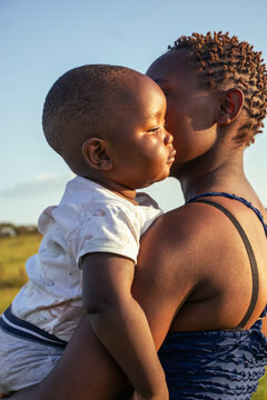 A beautiful young African woman playing with her baby boy outdoors at sunset