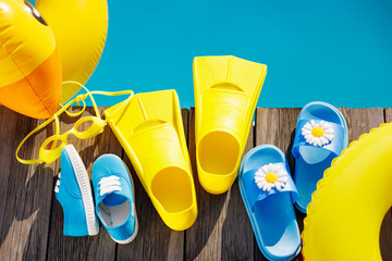 Beach flip-flops and sunglasses on wooden planks near swimming pool