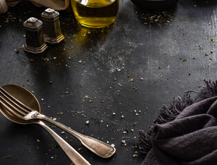 Empty black table with olive oil, salt and pepper, napkin and cutlery on side
