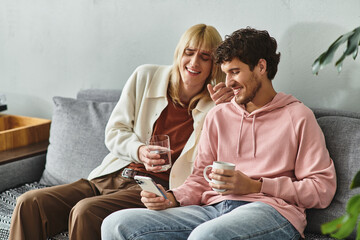 Two happy men enjoy each others company on a cozy couch with drinks and smiles at home