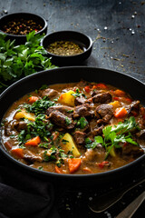Beef stew with vegetables and potatoes on black table