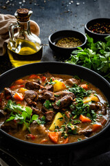 Beef stew with vegetables and potatoes on black table