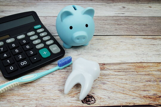 Toothbrush dental hygiene concept with calculator and piggy saving on wooden background, Dental money and dentist treatment costs