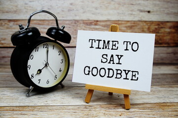 Time to say Goodbye text written on paper card with alarm clcok on wooden background