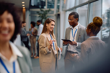 Multiracial group of business people talking in hallway of office building.