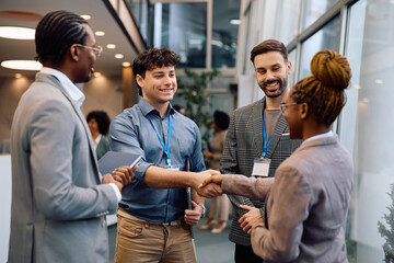 Happy colleagues greeting while attending business seminar in conference hall.