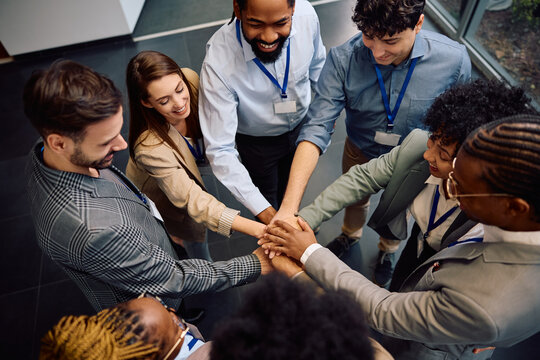 Above view of team of happy entrepreneurs gathering their hands in unity.