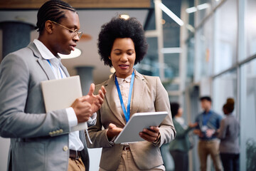 Black colleagues using digital tablet during business conference in board room.