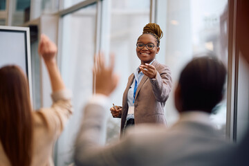 Happy black business seminar speaker pointing at attendee who wants to ask question in conference...