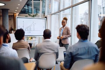 Black female speaker talking on business seminar in conference room.