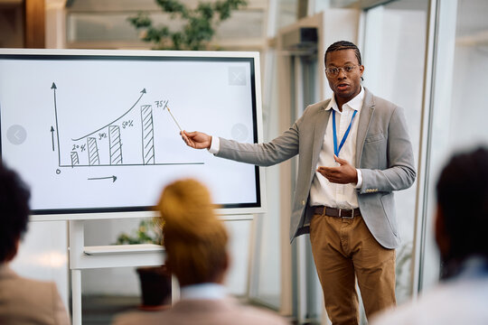 Black businessman giving presentation during conference in board room.