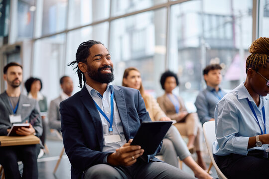 Happy black businessman using touchpad during seminar in board room.